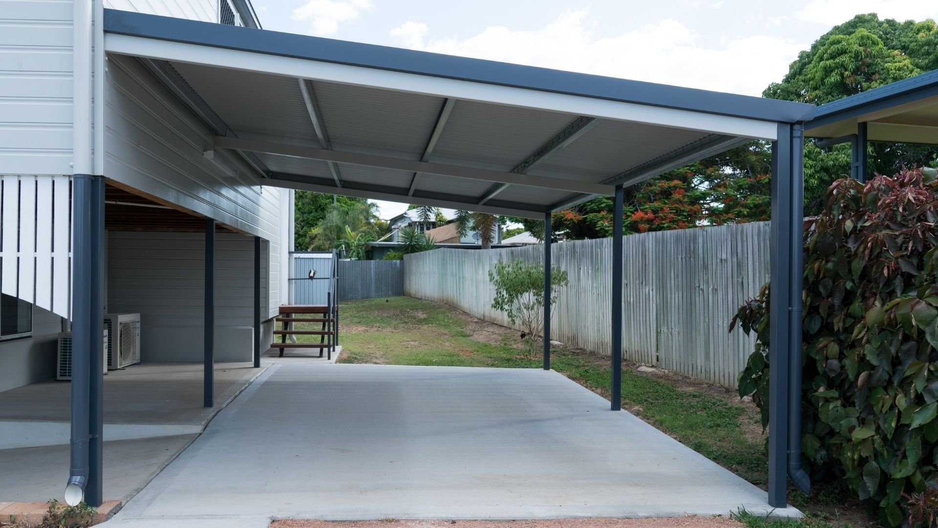 Modern backyard patio with metal pergola, concrete driveway, and metal fencing