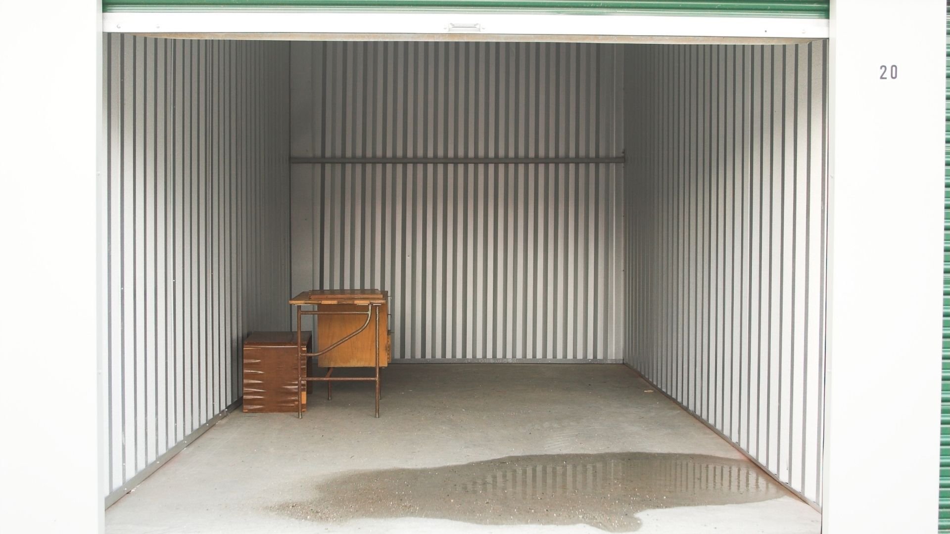 Storage unit interior with wooden desk and filing cabinet on concrete floor